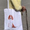 Frau trägt bedruckte, weiße Tasche mit Henkeln mit einem Welsh Springer Spaniel Welpen